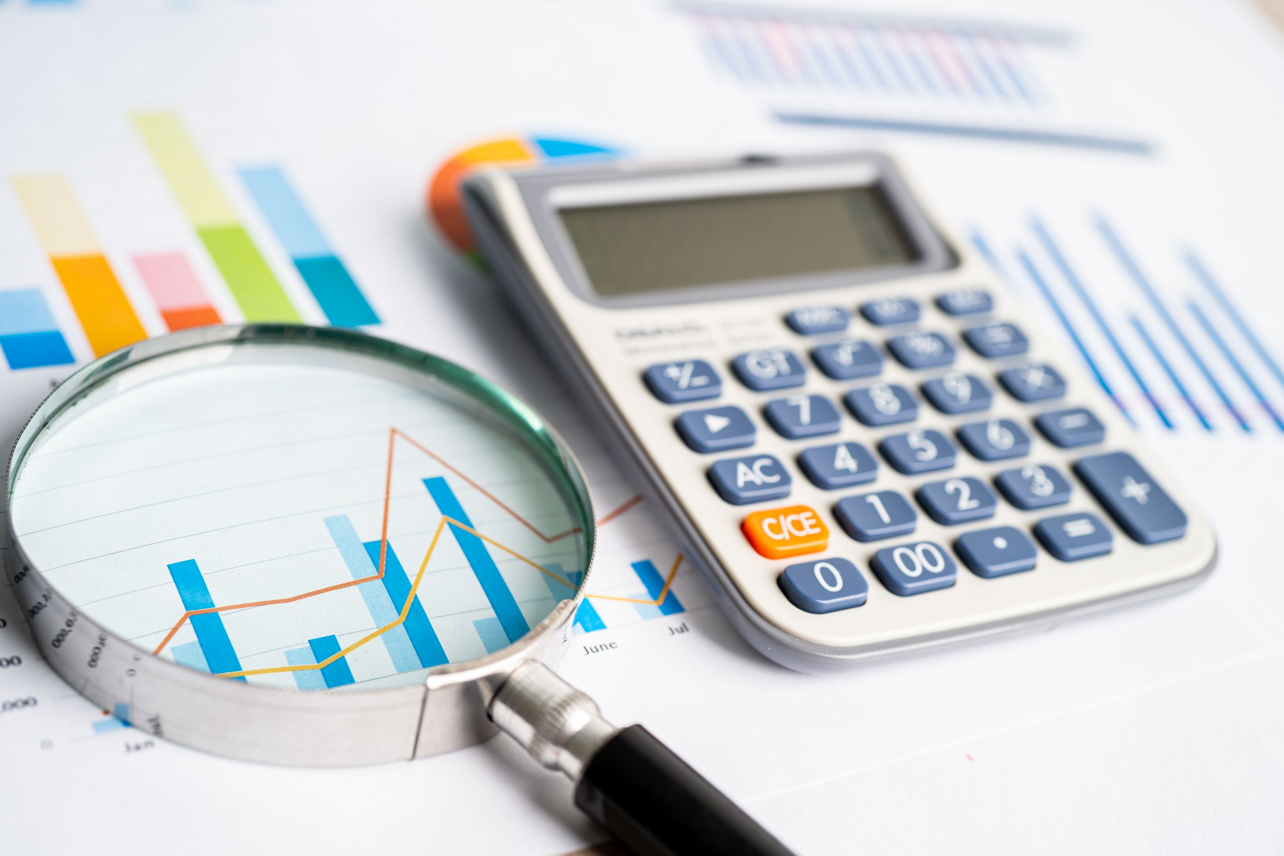 Magnifying glass and calculator on charts graphs paper. Financia